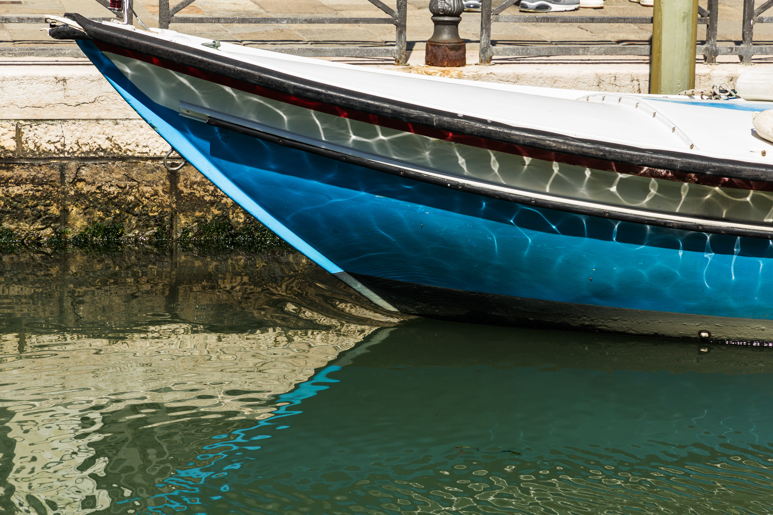Reflexe im Kanalwasser am blauen Bootsbug