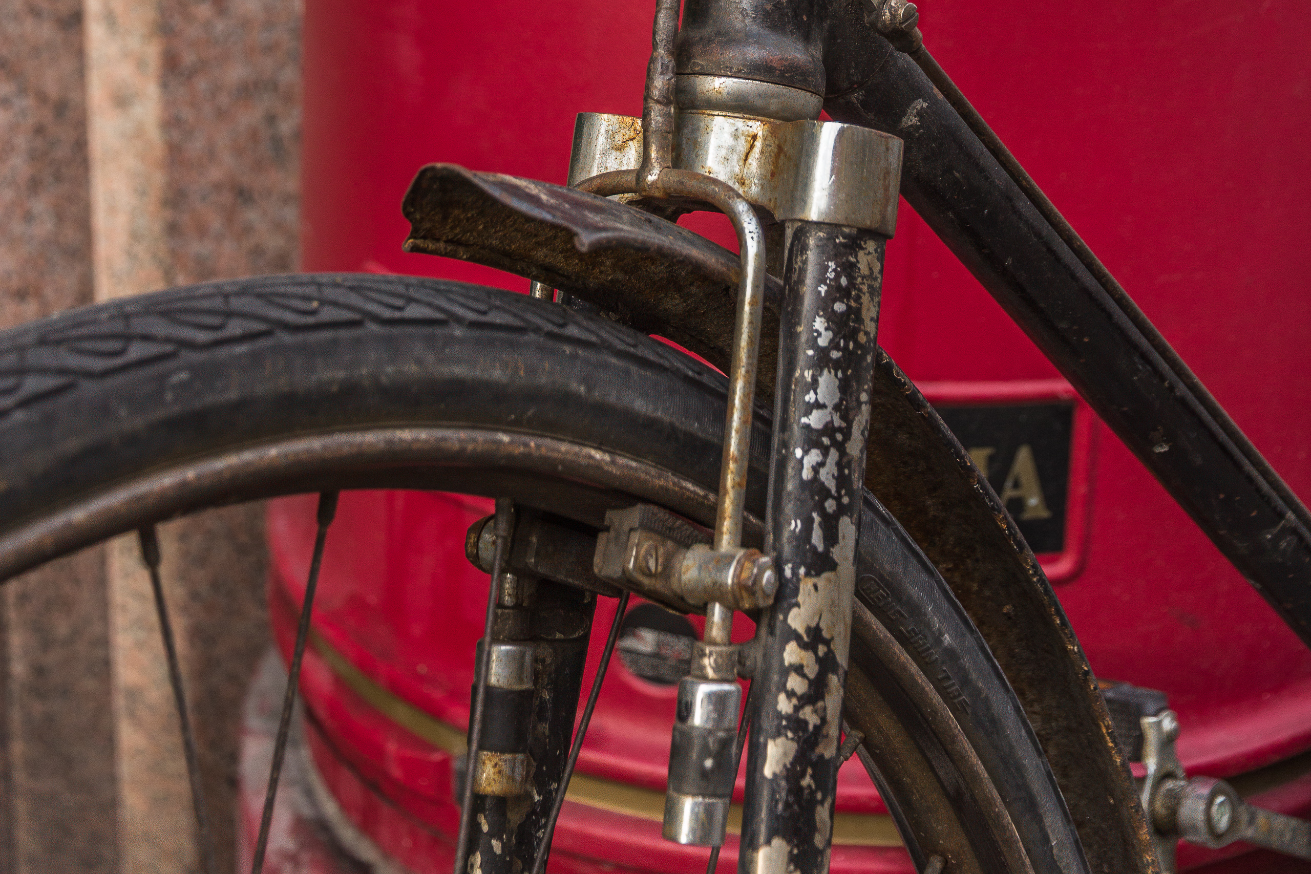 Detail eines alten Fahrrads vor roter Wand