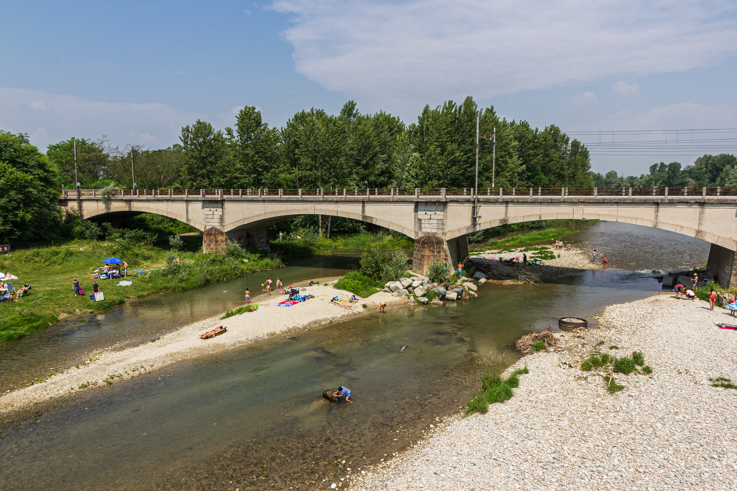 Badeplatz am Fluss unter einer alten Steinbogenbrücke