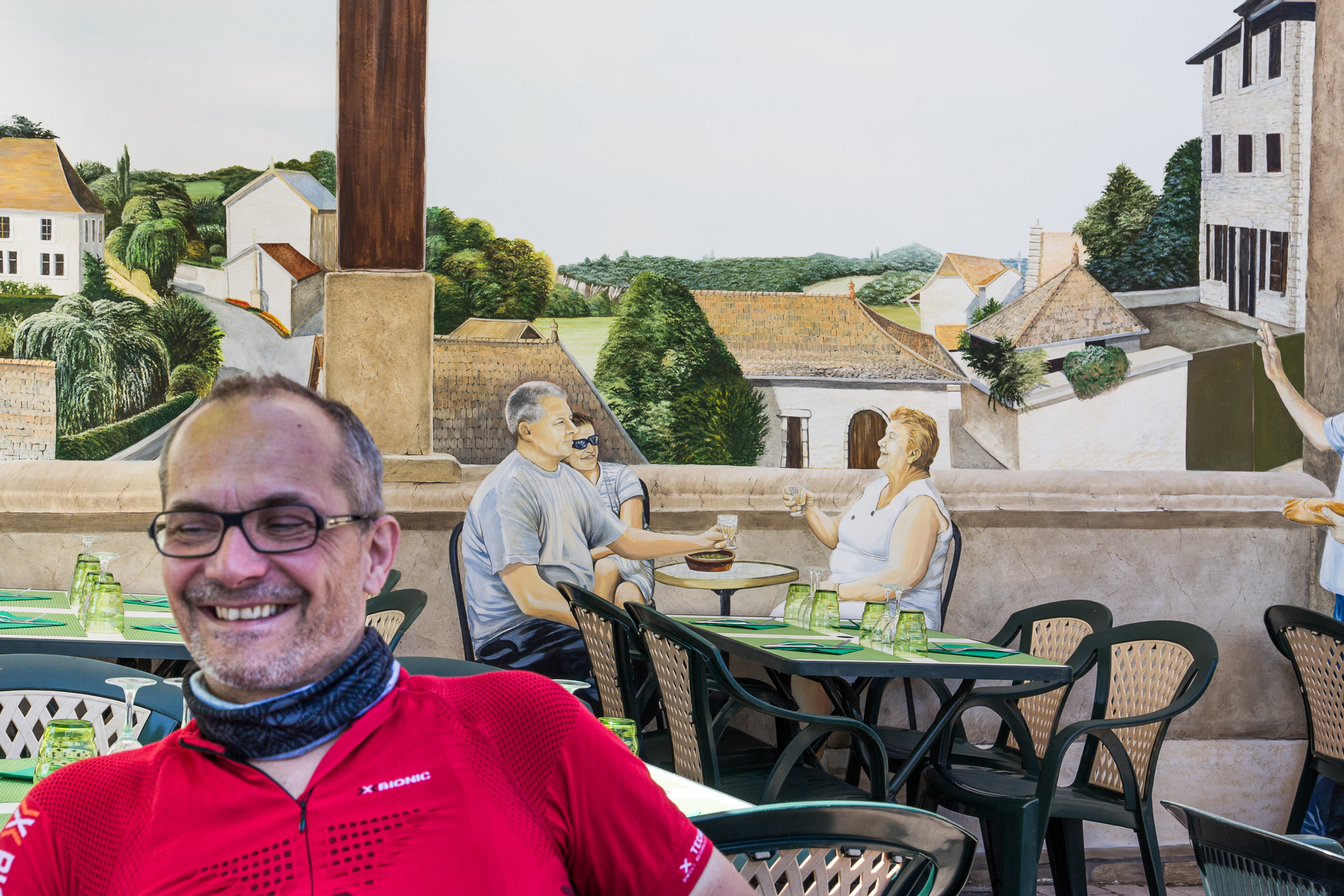 An der Restaurant-Terrasse vor einem Trompe-l'œil-Wandbild