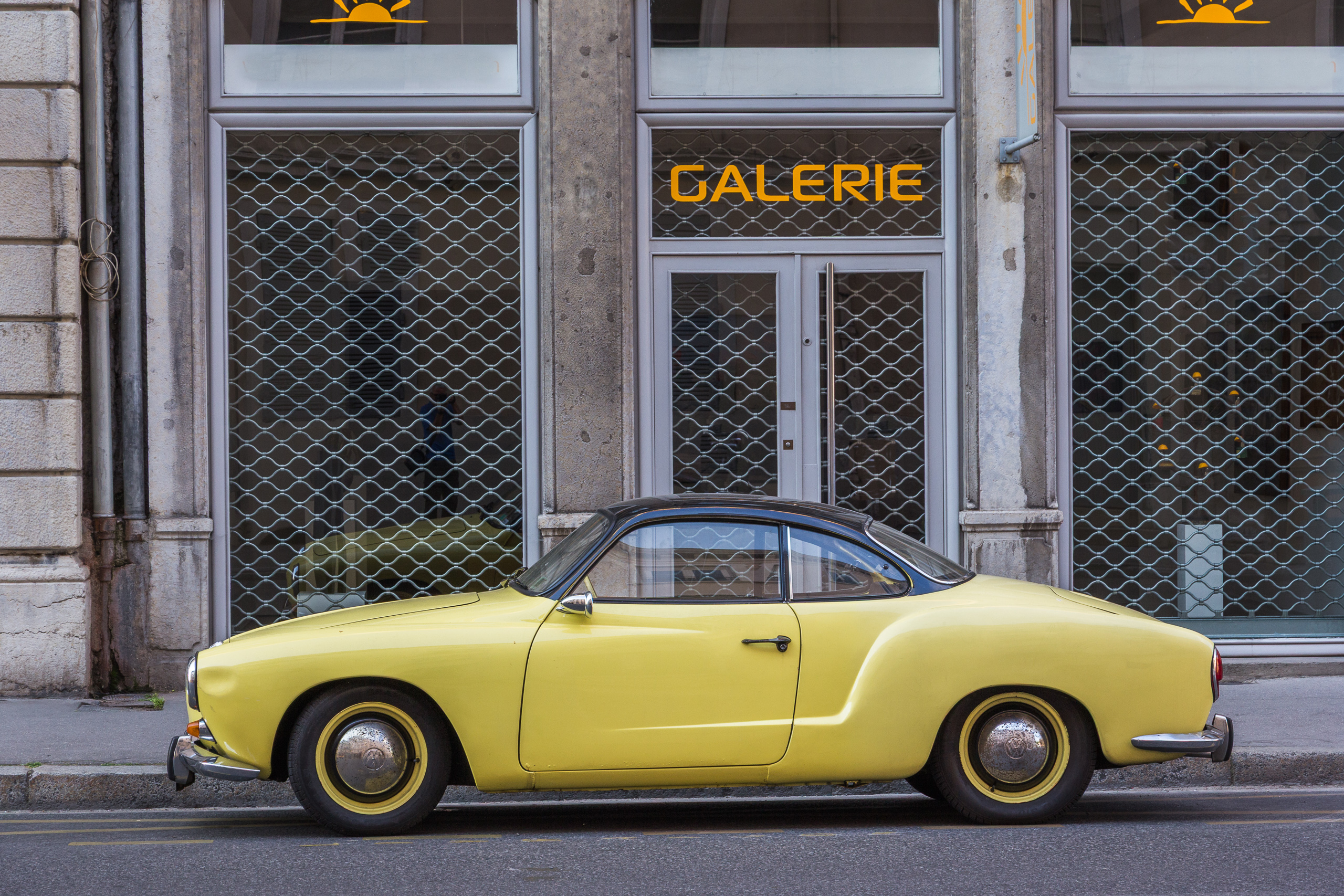 Ein gelber VW Karmann Ghia vor einer Galerie