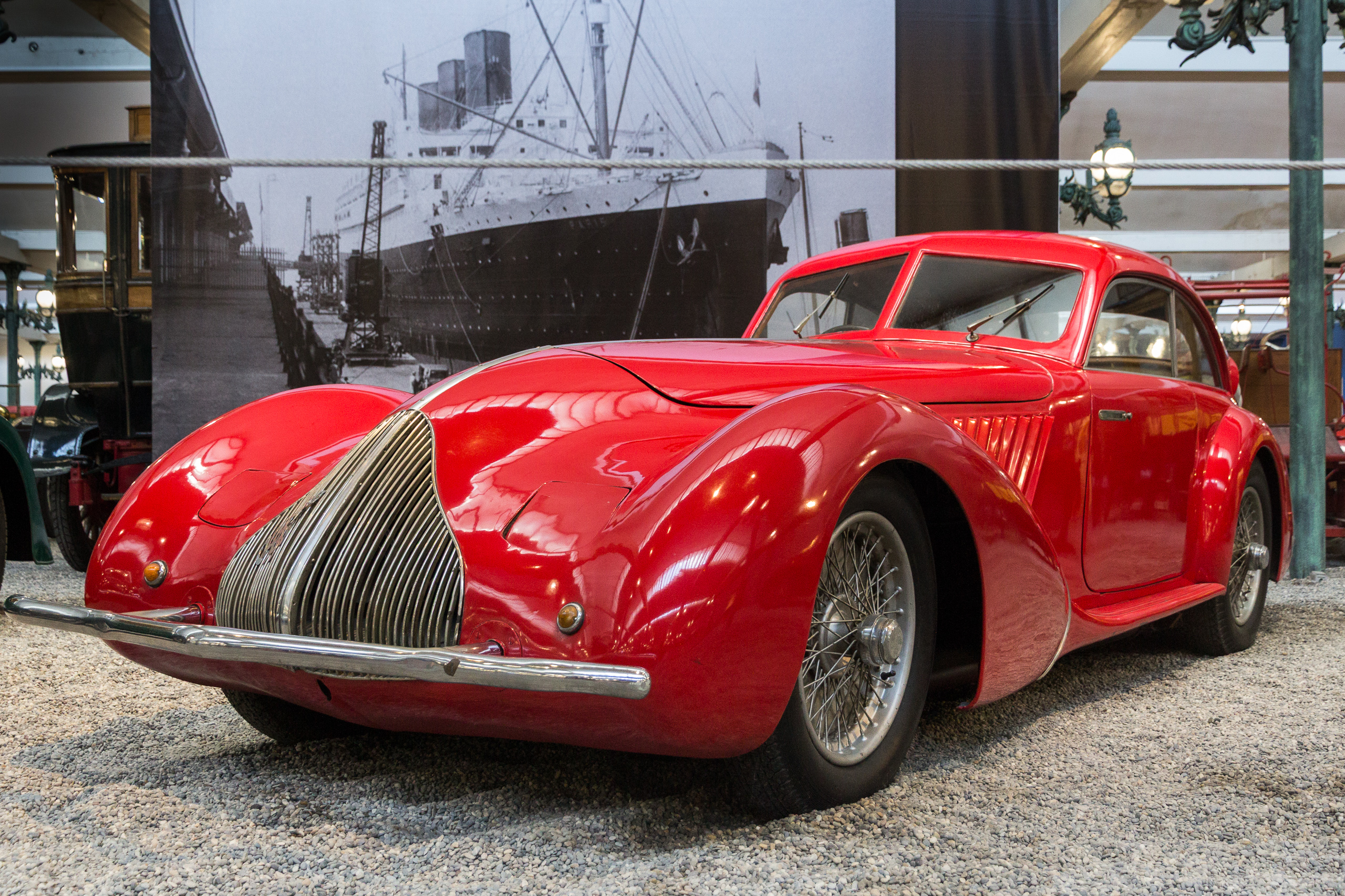 Rotes Alfa-Romeo-Coupé vor dem Hafenfoto an der Hallenwand