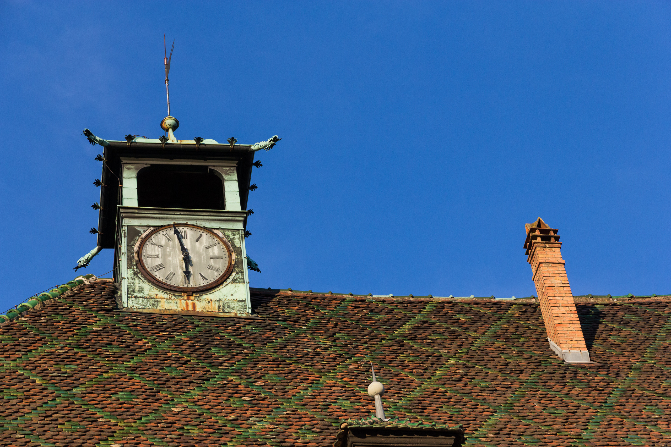 Dachreiter mit Uhr über den bunt glasierten Ziegeln